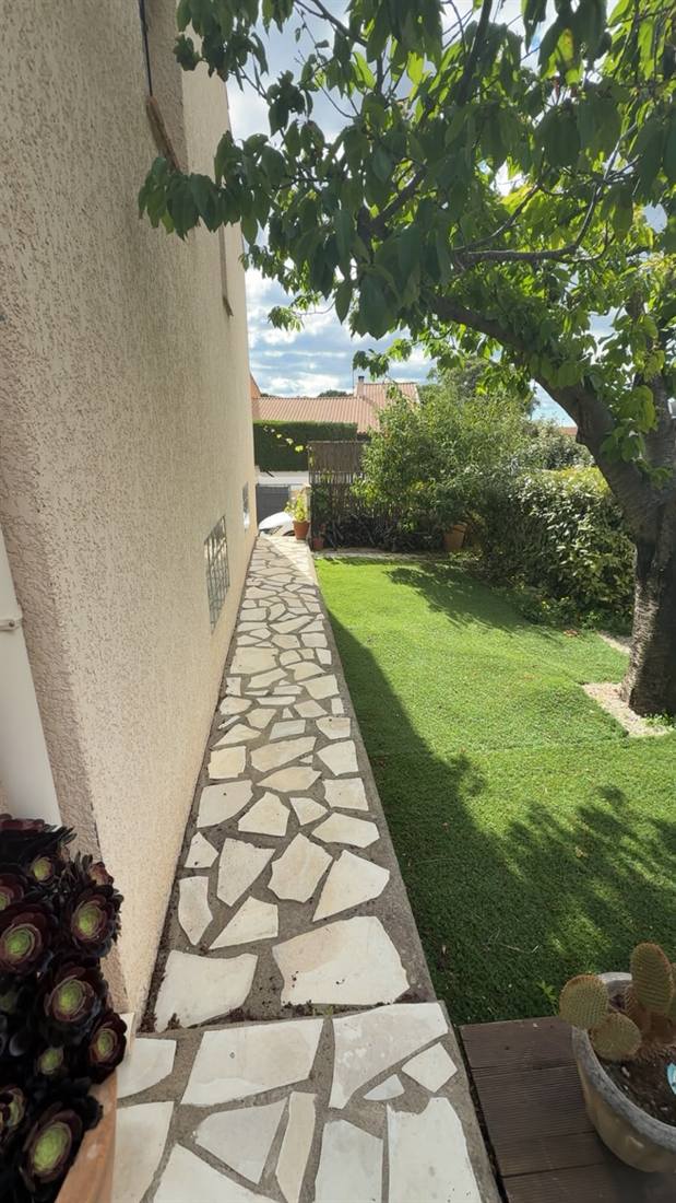 Allée de jardin en dallage pierre naturelle le long d'une maison à Béziers, Hérault